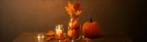 Fall inspired glass vase decoration with pumpkins, autumn leaves, candle, and rustic cozy setting