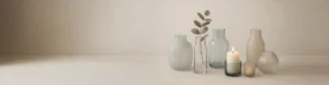Elegant arrangement of neutral-tone glass vases and candle holders featuring 2025–2026 color trends in soft gray, pale blue, and beige hues.