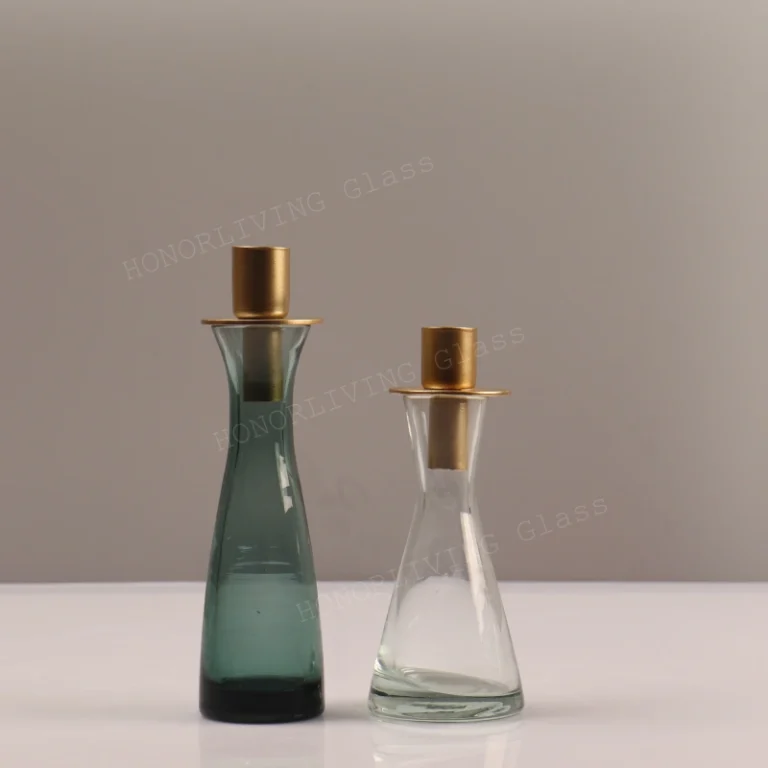Two HonorLiving glass vases: teal green and clear, each with a gold metal candle holder accessory.