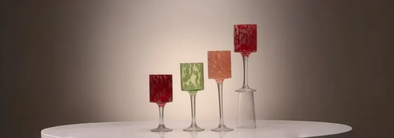 Set of four colored long stem glass candle holders with delicate color dots inside the glass