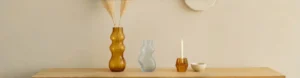 Amber glass vase and matching amber glass candleholder displayed on a beige wooden table, showcasing modern home decor style.