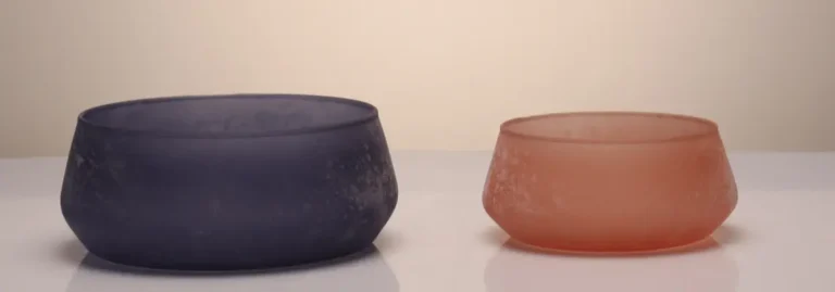 Set of two frosted colored glass bowls in soft pastel tones with a smooth matte finish