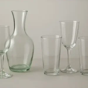 Hand-blown glassware beside machine-made glassware, showing the visual differences in craftsmanship and production quality.