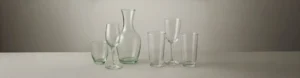 Hand-blown glassware beside machine-made glassware, showing the visual differences in craftsmanship and production quality.