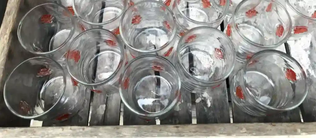Clear glass cups with red printed patterns arranged in rows during production process in glassware manufacturing